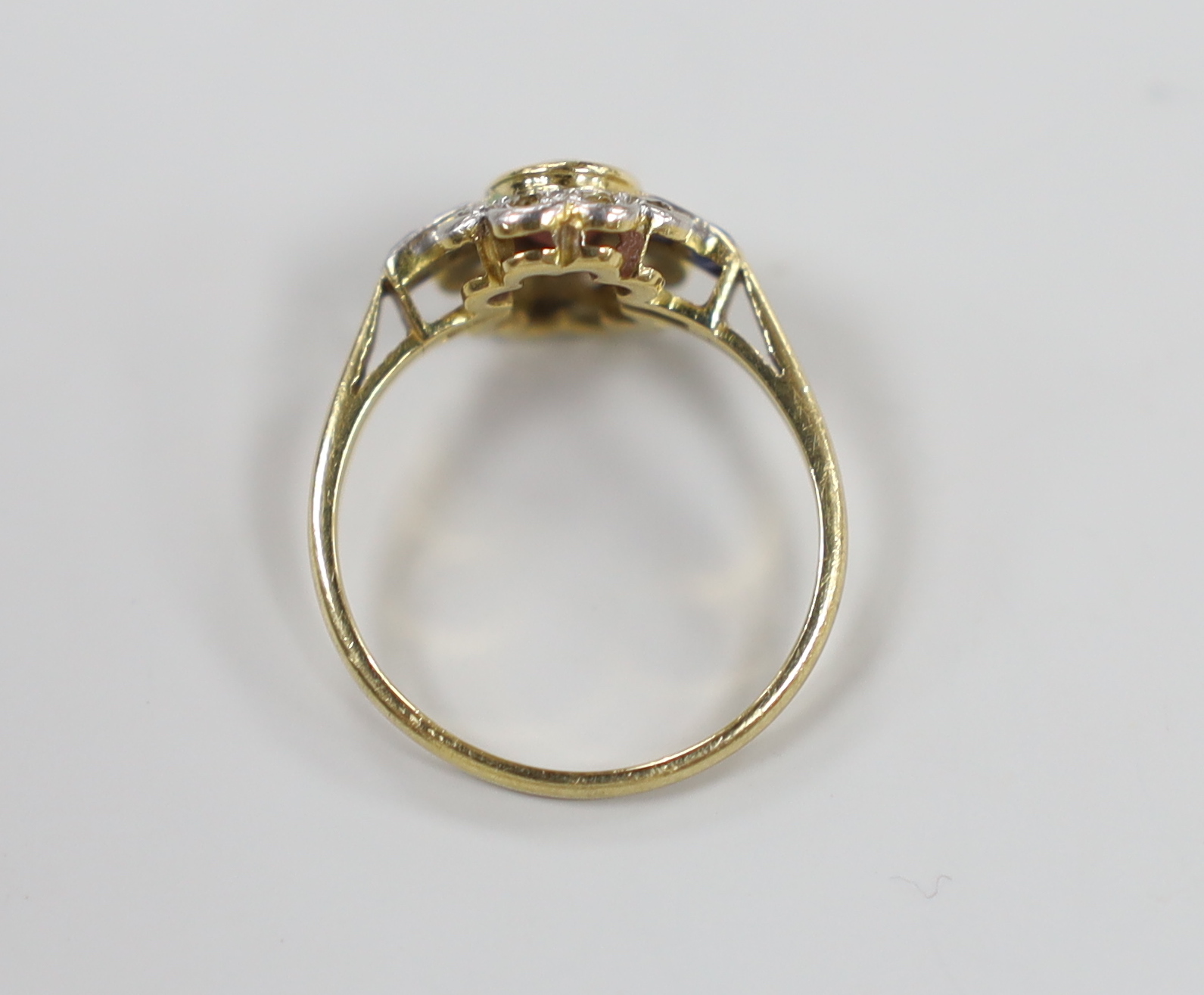 A 1920's/1930's yellow metal, ruby, sapphire and diamond set oval cluster ring, size O, gross weight 3.1 grams.